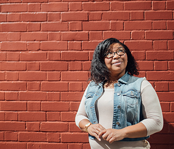 Smiling young woman in front of red brick wall