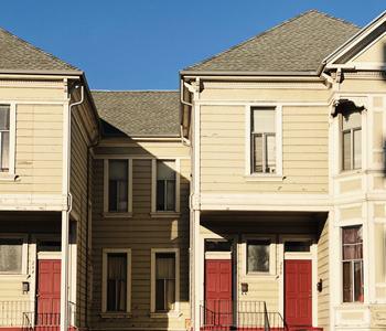 Photo of duplex units with red doors // Howie Mapson / unsplash.com